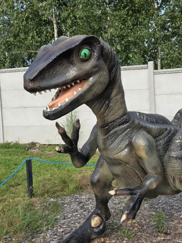 Figura drapieżnego dinozaura z zielonym okiem i otwartą paszczą