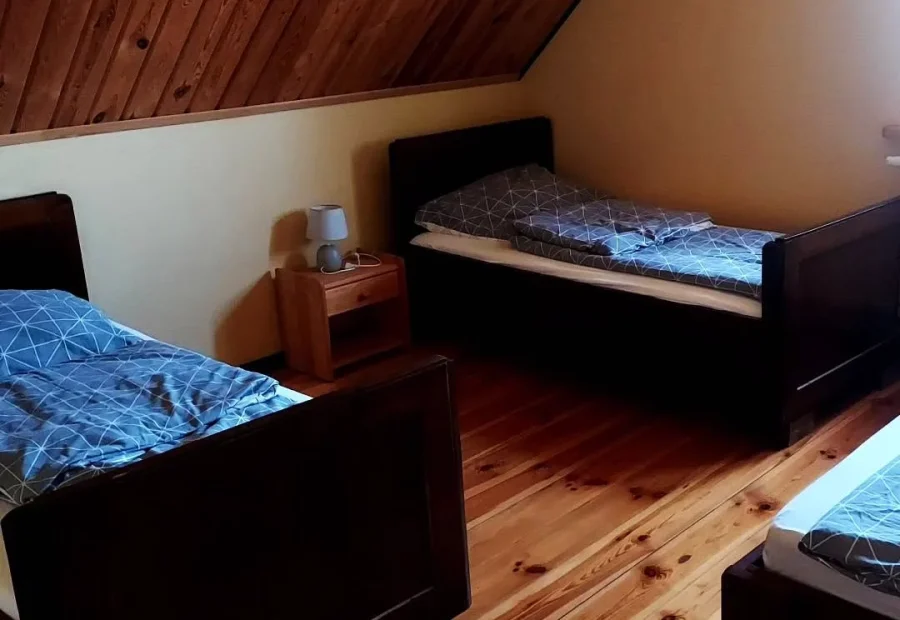 Sypialnia na poddaszu domku z drewnianymi łóżkami