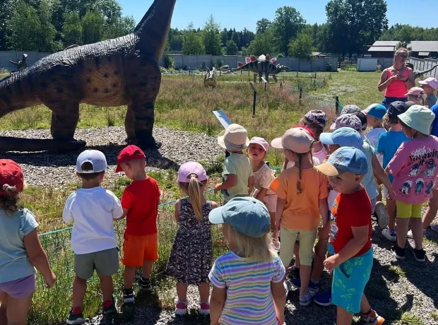 Grupa dzieci ogląda model długoszyjego dinozaura