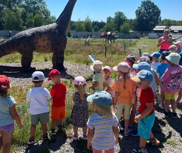 Grupa dzieci ogląda model długoszyjego dinozaura