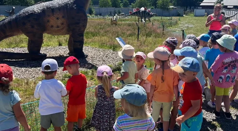 Grupa dzieci ogląda model długoszyjego dinozaura