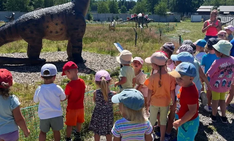 Grupa dzieci ogląda model długoszyjego dinozaura
