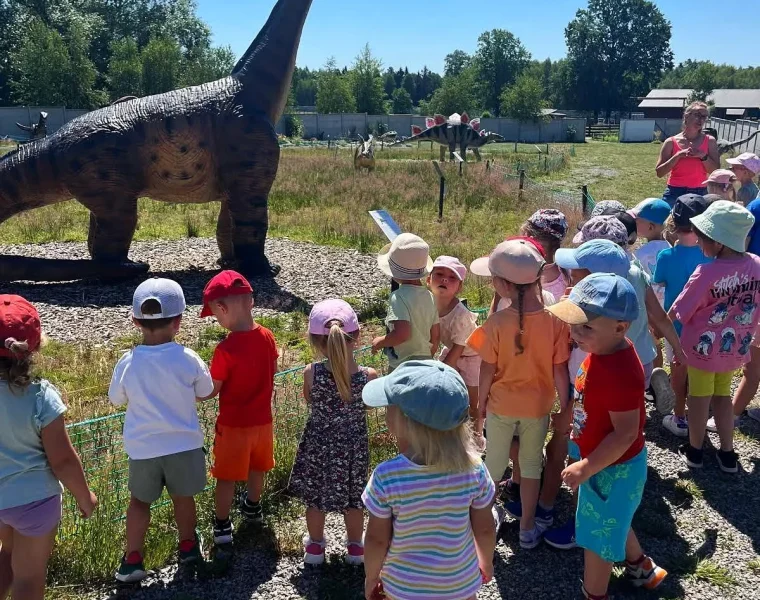 Grupa dzieci ogląda model długoszyjego dinozaura