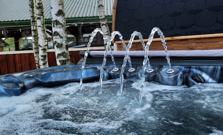Jacuzzi z fontannami wody na tle sauny w kształcie beczki