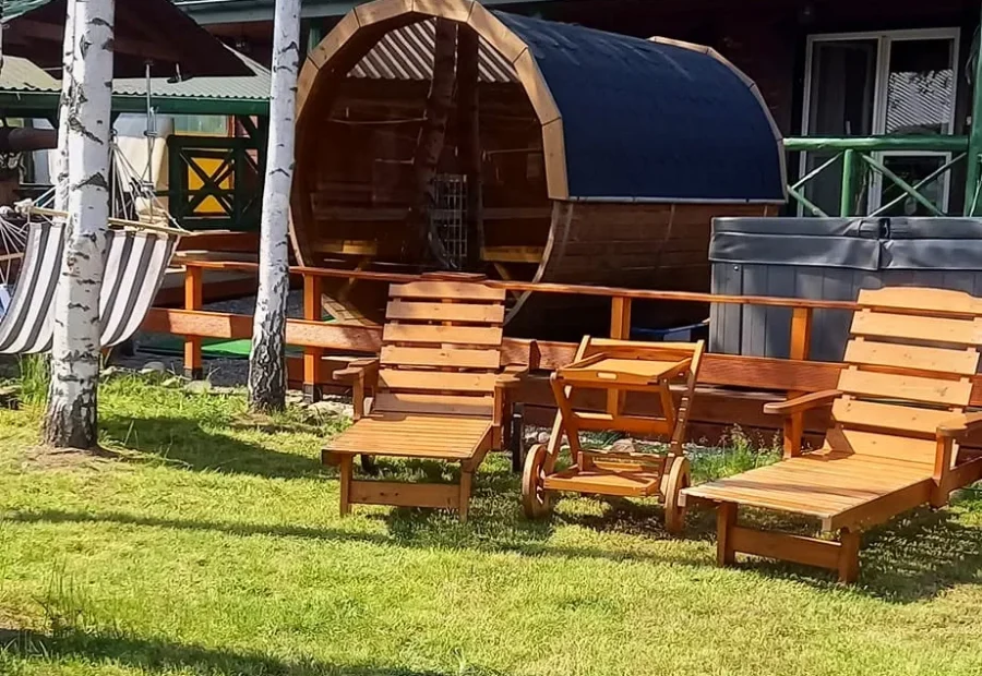 Sauna w kształcie beczki, jacuzzi i drewniane leżaki na trawie