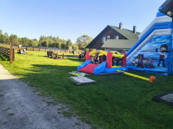 Dmuchany zamek i wysoka dmuchana zjeżdżalnia na trawie przy domu